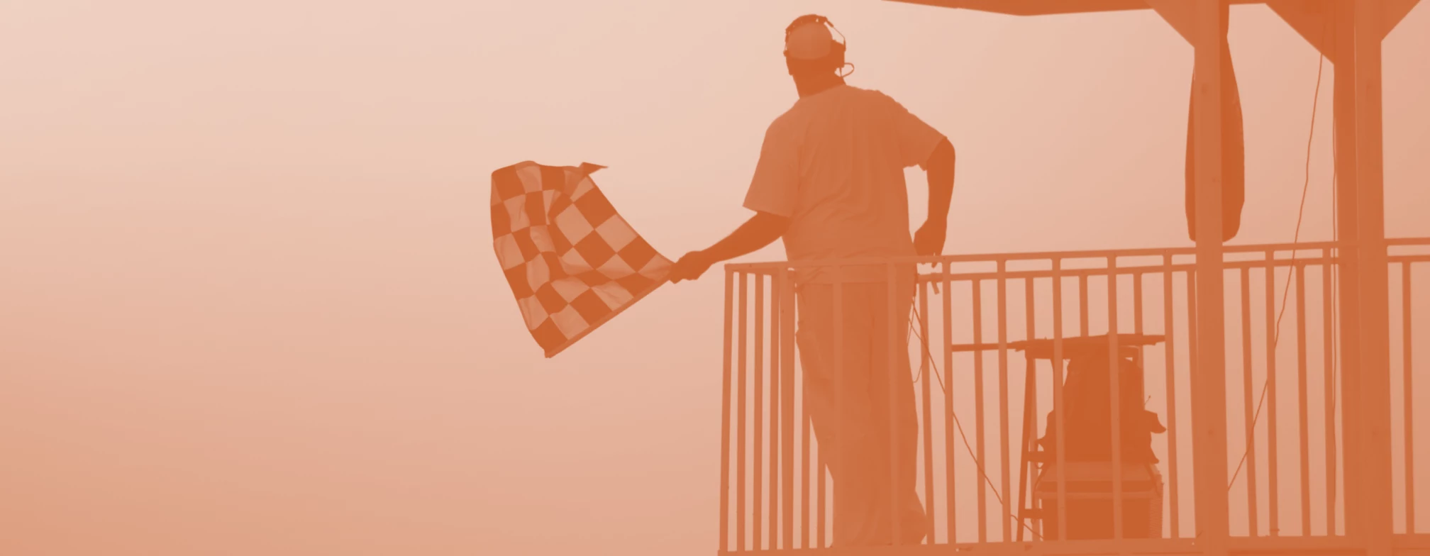 Fotografia de um operador de corrida sinalizando com uma bandeira quadriculada